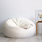 ivory fur beanbag on wooden floor with book resting on it