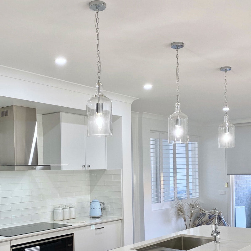 glass jug pendant light hanging in a white kitchen with smeg appliances and white window shutters