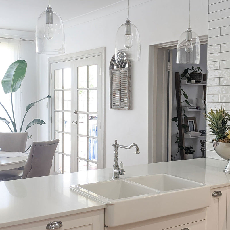 dome shape glass pendant light with polished chrome hardware hanging in a white farmhouse kitchen