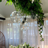 round glass pendant light with polished chrome hardware hanging in a wedding reception space