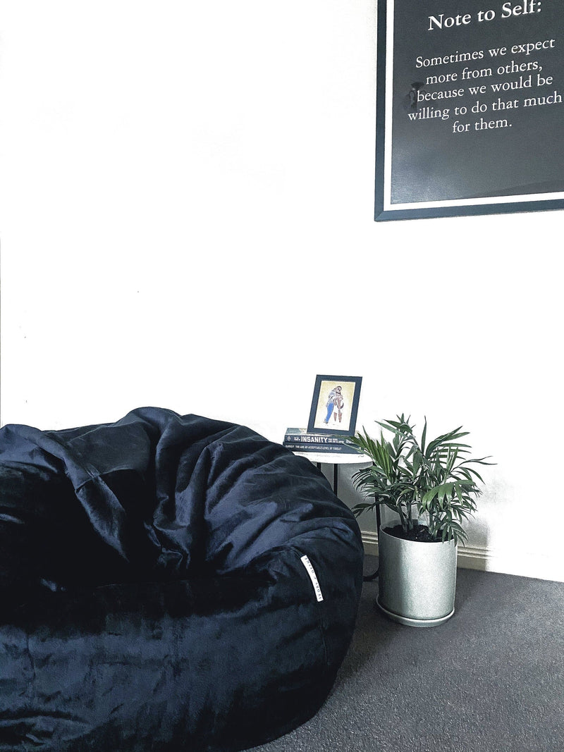extra large black Pierre fur beanbag next to a palm plant on the floor