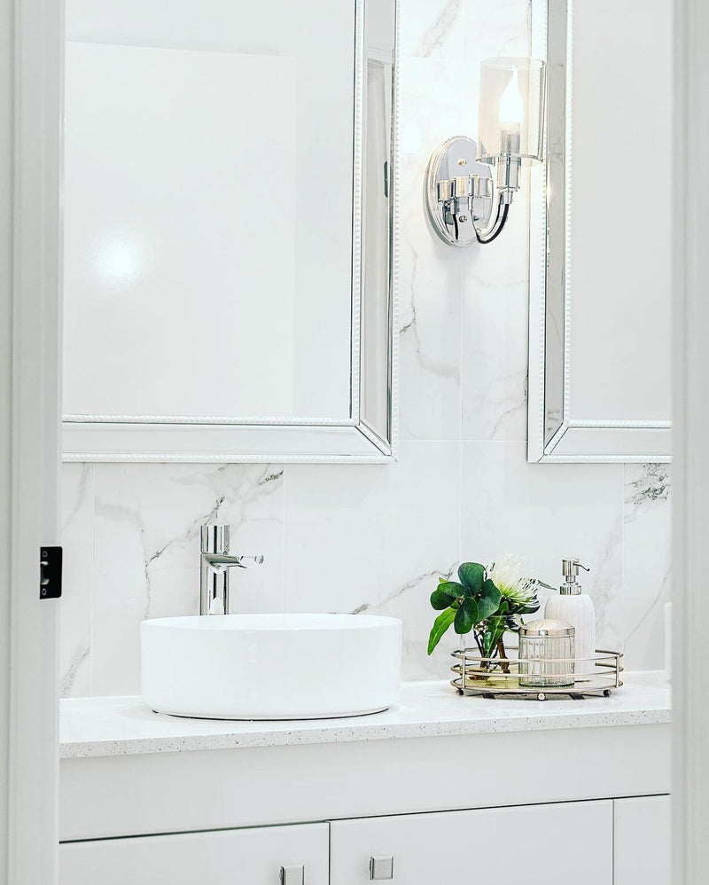 chrome wall light in a white bathroom with marble walls