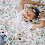Kid lying in foam pit laughing
