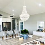white rope pendant light hanging in a kitchen with white rattan bar stools and a white hampton buffet