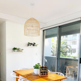 large 45cm rattan pendant hanging in a dining room with plants and white dining chairs
