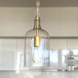 kendal glass pendant light with gold hardware hanging in a white kitchen