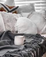 luxury bamboo blanket throw on a couch with natural cushions and a stoneware cup