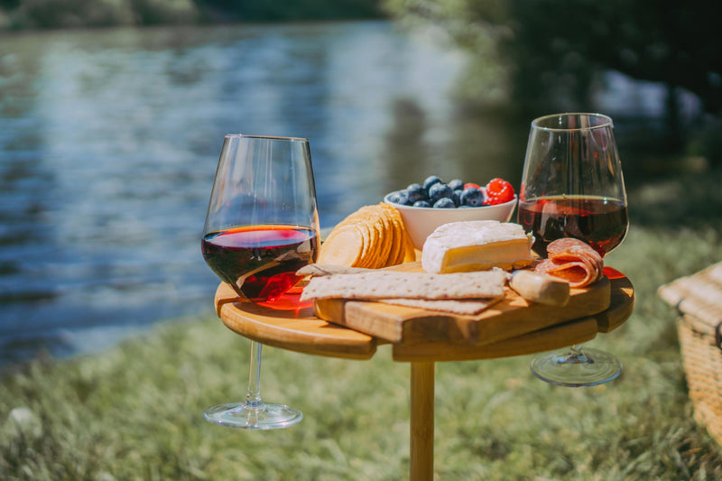 enjoying the river with a bamboo picnic table full of wine and cheese