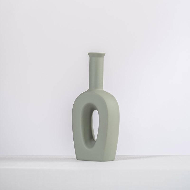 sage ceramic vase on a white shelf