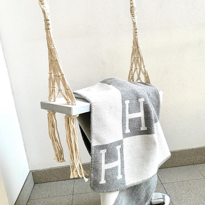 wooden boho swing with tassels hanging outdoors with a hermes blanke