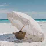 bora bora beach umbrella with fringe on a sandy beach by the ocean