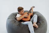 boy playing guitar in a fur bean bag