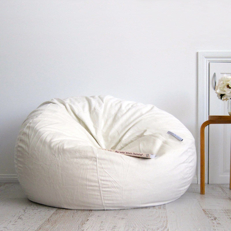 ivory fur beanbag on wooden floor with book resting on it