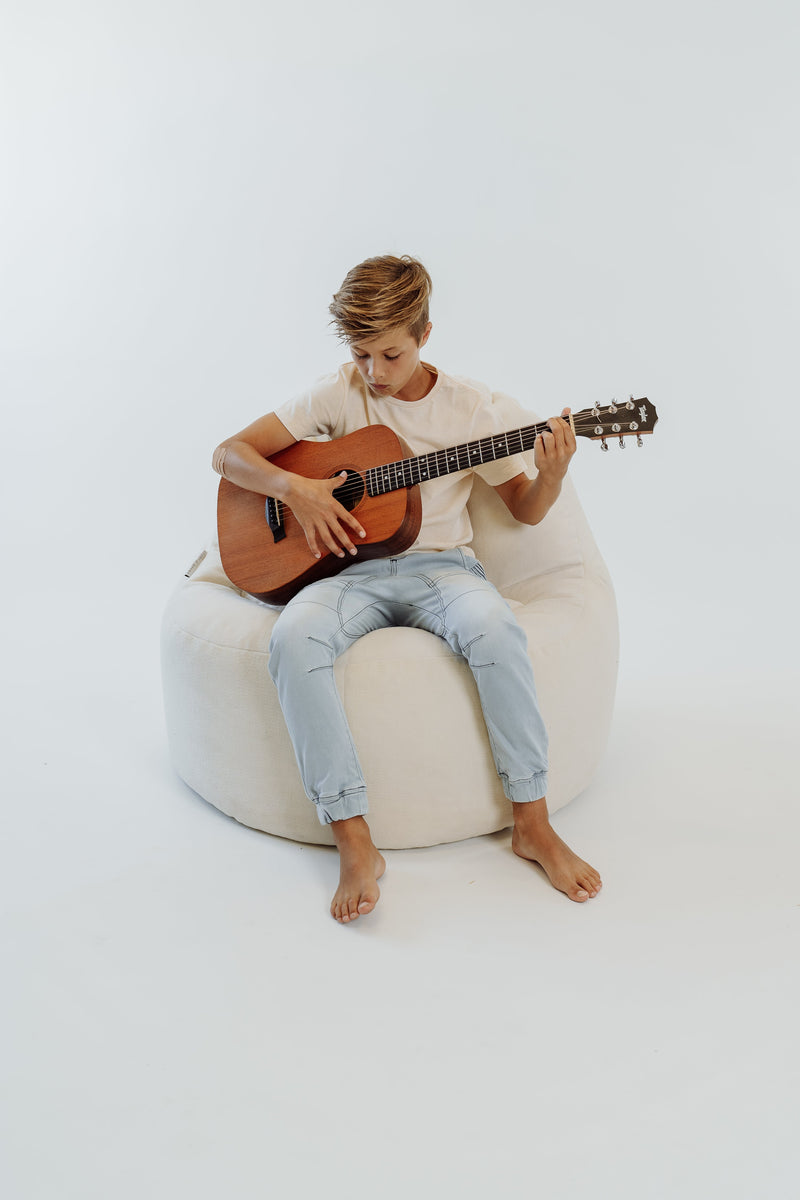 boy playing guitar in a cream plush lounger bean bag