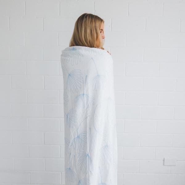 girl wrapped in midsummer dream towel standing against a white brick wall